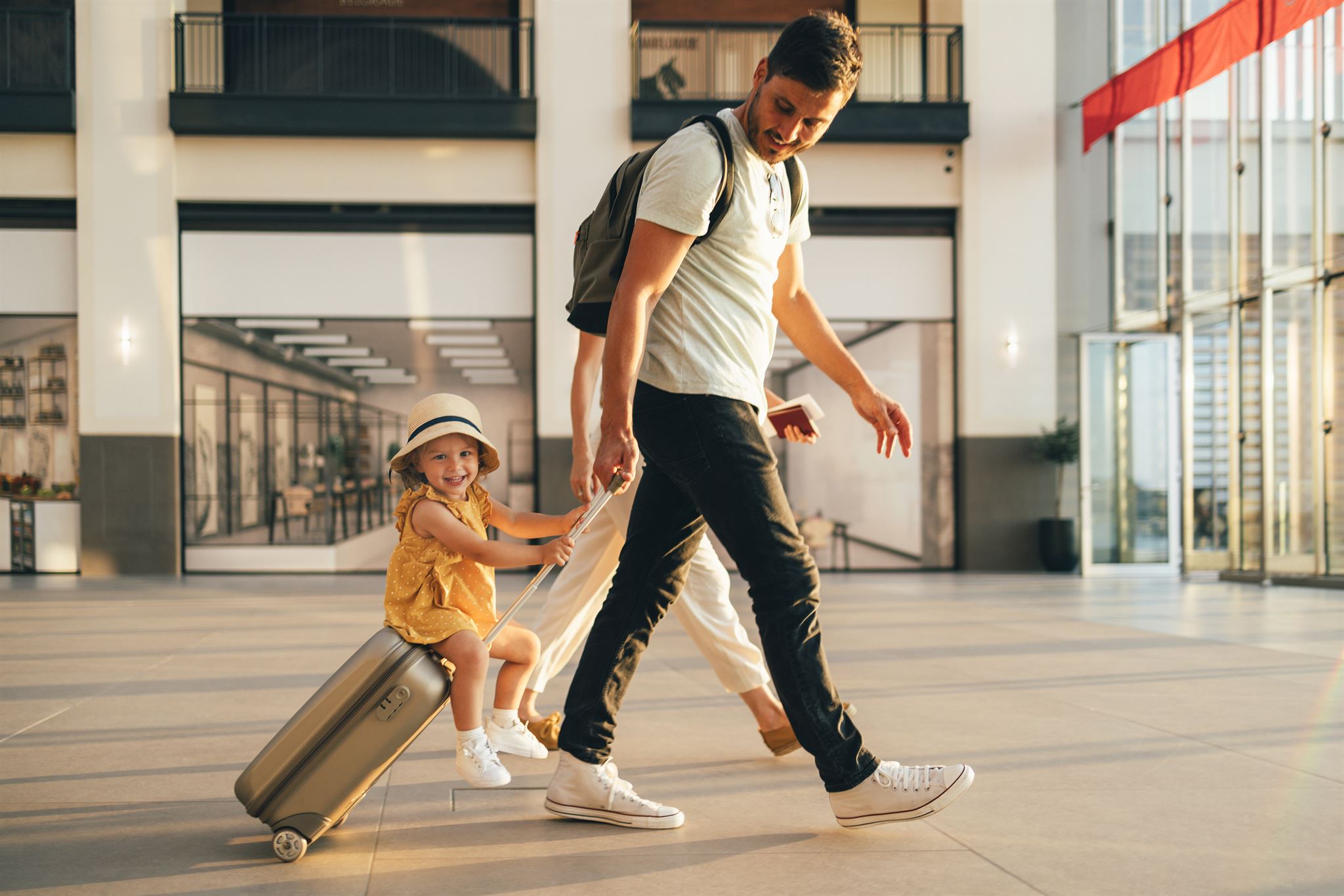 Couple-walking-with-girl-riding-luggage