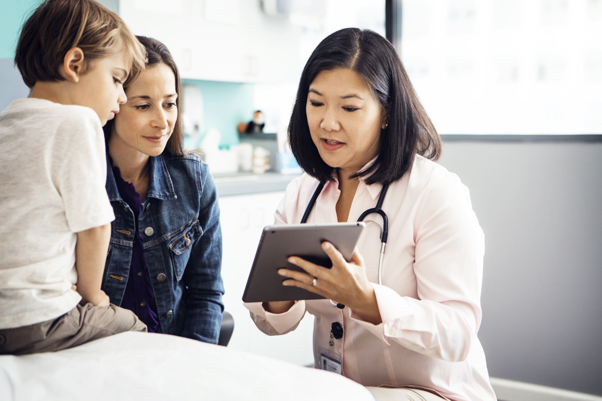 Doctor-in-clinic-explaining-report-on-tablet-to-family